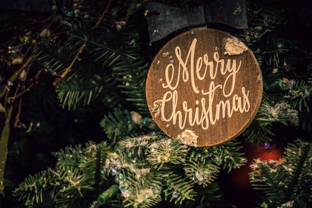Zbliżenie na choinkę i drewniany krążek z napisem Merry Christmas 